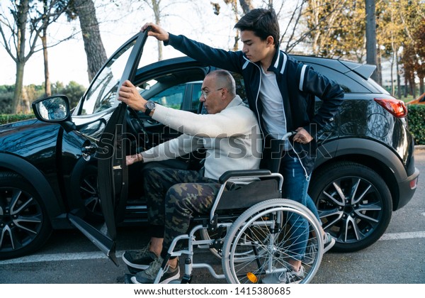 Boy\
helping his grandpa handicapped to get on the\
car
