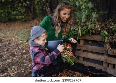 Boy helping mother to put kitchen waste, peel and leftover vegetables scraps into composter in the garden. Concept of composting kitchen biodegradable waste. - Powered by Shutterstock