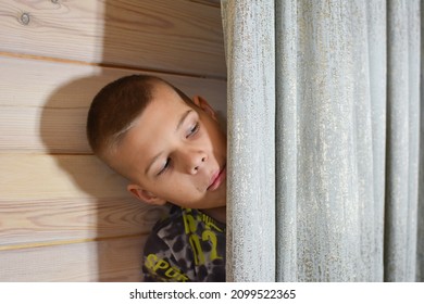boy hides behind a curtain in the room. kids hide and seek