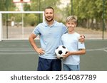 Boy with his dad playing football on field