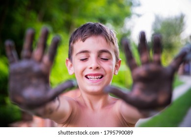 The Boy With His Eyes Closed Shows His Muddy Hands To The Camera