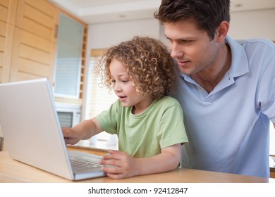 Boy and his father using a notebook in their kitchen