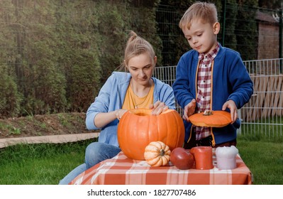 A boy and his mother cut a pumpkin. A young mother and son are preparing a pumpkin for Halloween. Peel an orange pumpkin.