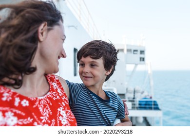 A boy and his mother stand on the deck of a ship and look at the sea, a family travels on a cruise ship, a trip across the ocean, a woman and her son look at the water.