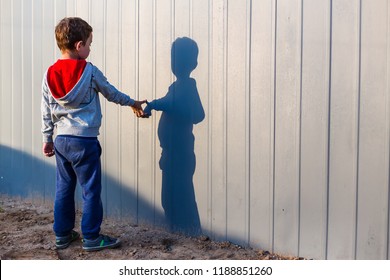 boy and his shadow. Lonely little child playing with his shadow outside. the concept of autism and loneliness. Copy space for your text