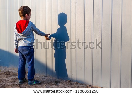 boy and his shadow. Lonely little child playing with his shadow outside. the concept of autism and loneliness. Copy space for your text