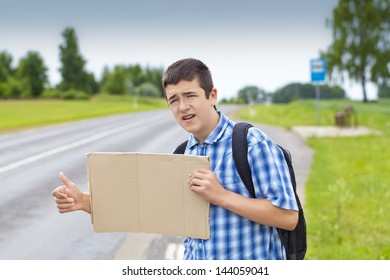 Boy hitchhiker on the road waiting for car to stop