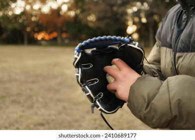 A boy holding a ball, before throwing it. Baseball glove. Left handed. Grass Baseball, vacation, sports, practice, park, afternoon.  Fall or Winter, beginner pitcher.
