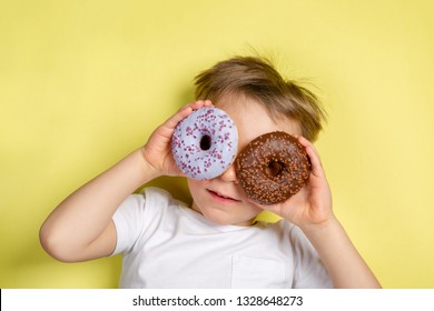Boy holding donuts by this eyes, bright background, top view