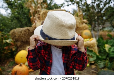boy holding his hat against the background of dad and garden