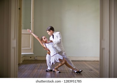 Boy Holding His Sister In A Dip As They Dance In A Room.