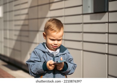 Boy Holding Mobile Phone Near To Parcel Locker Collecting Parcel From Shopping Locker. Child Skans QR Code On Mobile Phone Self-service Locker Cell With Bar Code Reader Modern Shipping Concept