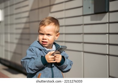 Boy Holding Mobile Phone Near To Parcel Locker Collecting Parcel From Shopping Locker. Child Skans QR Code On Mobile Phone Self-service Locker Cell With Bar Code Reader Modern Shipping Concept