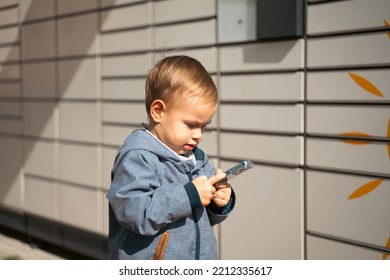 Boy Holding Mobile Phone Near To Parcel Locker Collecting Parcel From Shopping Locker. Child Skans QR Code On Mobile Phone Self-service Locker Cell With Bar Code Reader Modern Shipping Concept