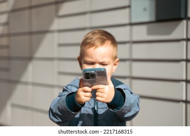 Boy Holding Mobile Phone Near To Parcel Locker Collecting Parcel From Shopping Locker. Child Skans QR Code On Mobile Phone Self-service Locker Cell With Bar Code Reader Modern Shipping Concept