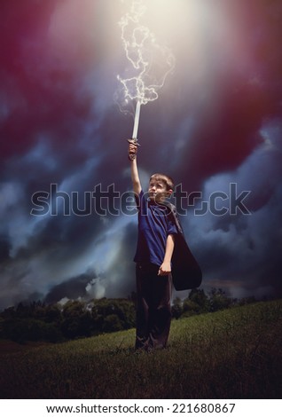 A boy is holding a sword and wearing a super hero cape with lightning bolts coming out of the sky for a imagination or pretend play concept.