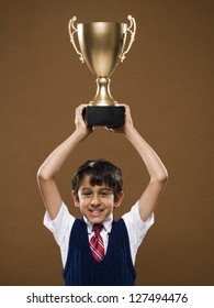 Boy Holding Trophy Cup Over His Head And Smiling