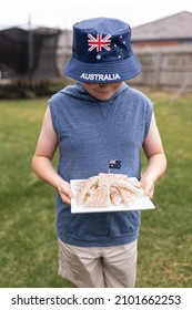 A Boy Holding A White Plate Of Iconic Traditional Australian Fairy Bread With An Aussie Flag Stuck In It For Australia Day, He Is Also Wearing A Bucket Hat With The Word Australia And The Flag