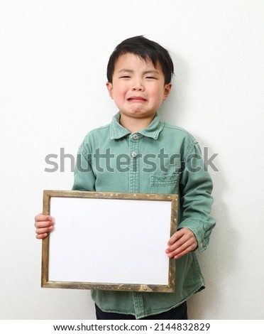 A boy holding a writable paper.