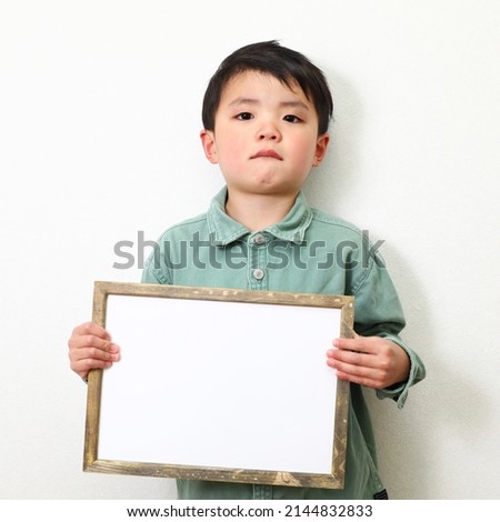 A boy holding a writable paper.
