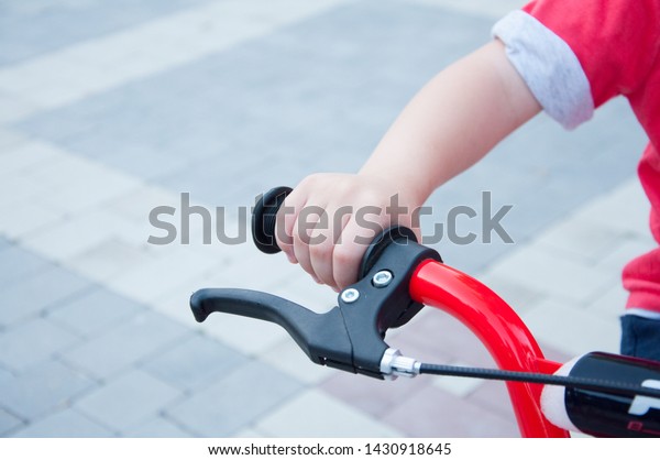 boy holds hand on bicycle. Mirror on the steering\
wheel. In the park in\
summer