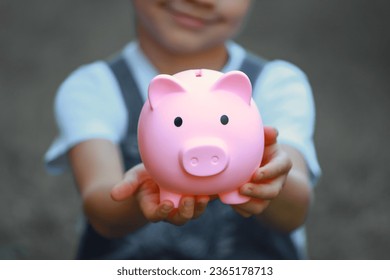 a boy holds a piggy bank.Piggy Bank.Money saving and deposit for investment to get profit and dividend concept. - Shutterstock ID 2365178713