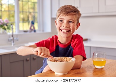 Boy At Home Eating Bowl Of Breakfast Cereal At Kitchen Counter