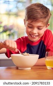 Boy At Home Eating Bowl Of Breakfast Cereal At Kitchen Counter