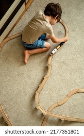 A Boy At Home In A Room Is Building A Railway, A Child Is Playing With A Toy Train. Educational Toys For Home And Kindergarten. Wooden Environmental Toys