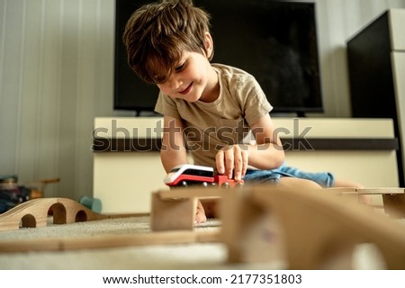 a boy at home in a room is building a railway, a child is playing with a toy train. Educational toys for home and kindergarten. Wooden Environmental Toys