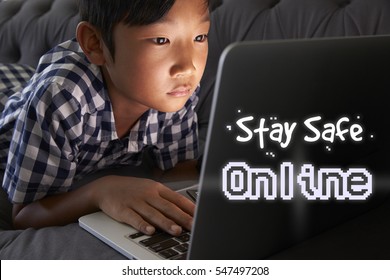 Boy At Home Using Laptop With Stay Safe Online Message