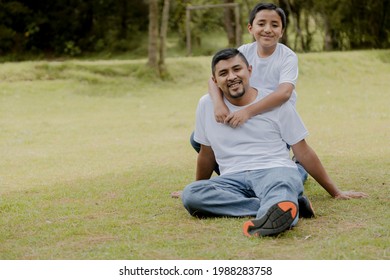 Boy Hugging His Father In The Field Enjoying Quality Time-Young Father With His Son Having A Fun Time In The Park