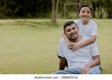 Boy Hugging His Father In The Field Enjoying Quality Time-Young Father With His Son Having A Fun Time In The Park