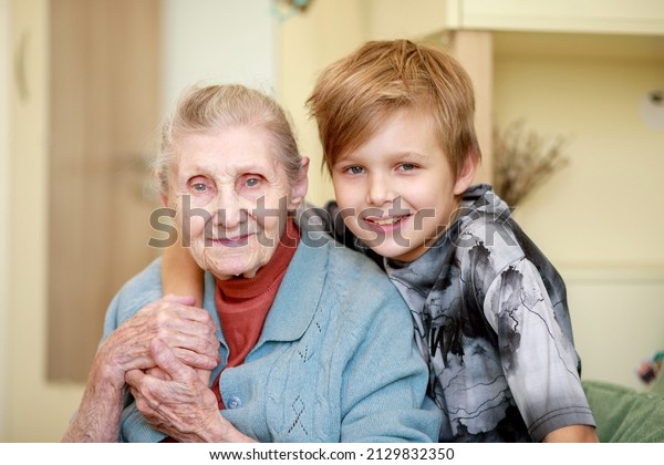 The\
boy hugs his grandmother, strong family ties, care for the older\
generation, grandson and great-grandmother at\
home.