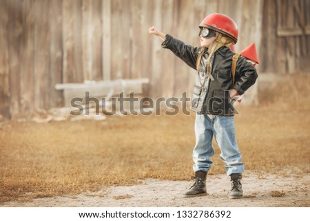 Boy in the image of a rocketman play in the backyard of the house