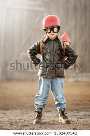 Boy in the image of a rocketman play in the backyard of the house