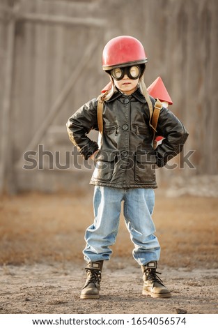 Boy in the image of a rocketman play in the backyard of the house