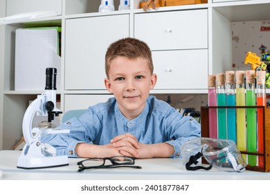 Boy in the image of a young scientist with flasks for chemistry and microscope. Boy is studying in the home laboratory. Science and education. - Powered by Shutterstock