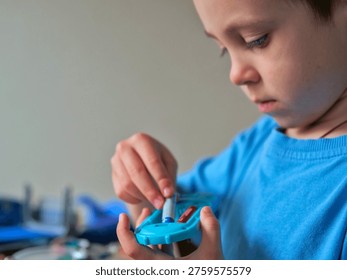 Boy Inserting Battery into Small Electronic Device — Child Reassembling Toy at Home Workbench, Hands-On Learning, STEM Curiosity and Problem Solving Concept
