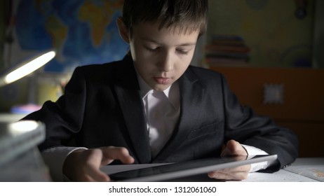 boy in jacket using tablet, doing homework at home, playing at the game
