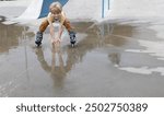 boy joyfully rides at speed on roller skates through a puddle after the rain, making splashes with his hands. mood to indulge, healthy lifestyle. Interesting fun childhood