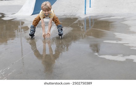 boy joyfully rides at speed on roller skates through a puddle after the rain, making splashes with his hands. mood to indulge, healthy lifestyle. Interesting fun childhood