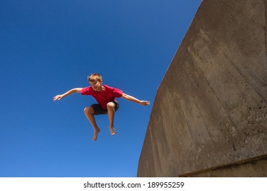 Boy Jumping Blue Sky Park Hour Teen Boy Park Hour Jumping Off Wall Against Blue Sky Onto Beach Parkour