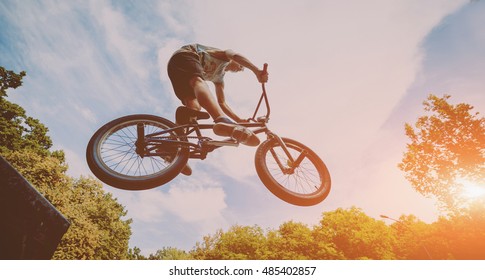 Boy jumping with his bmx in the park. Beautiful background
