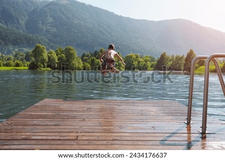 Boy jumping off the dock into the lake - a fun summer vacation. 