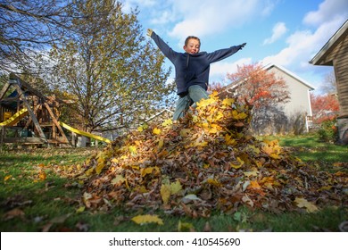 Boy Jumping In A Pile Of Autumn Leaves 