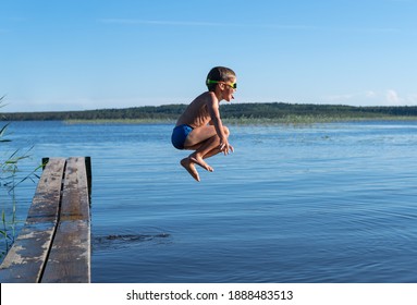 Boy Jumps Into Lake In Summer At Sunset.
