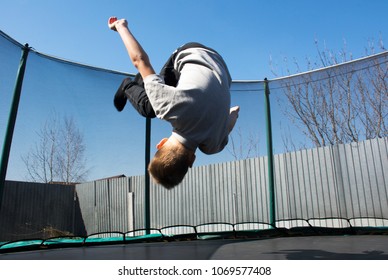 A boy jumps on a trampoline, does a somersault.A boy does a somersault on a trampoline. - Powered by Shutterstock