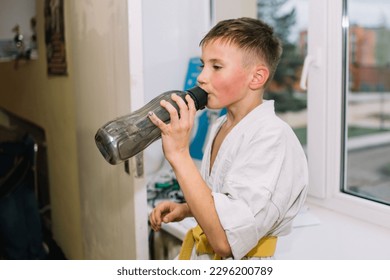 Boy in kemono drinking water after difficult karate sparring - Powered by Shutterstock