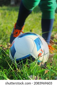 Boy kicking ball on green grass close up